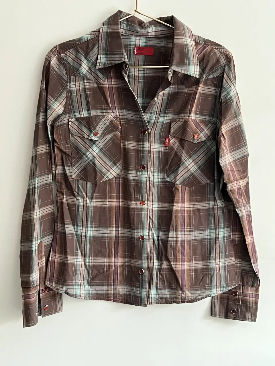 Camisa a cuadros marrón y celeste de la marca Levi's, con mangas largas y dos bolsillos delanteros. Ideal para un look casual y versátil.
