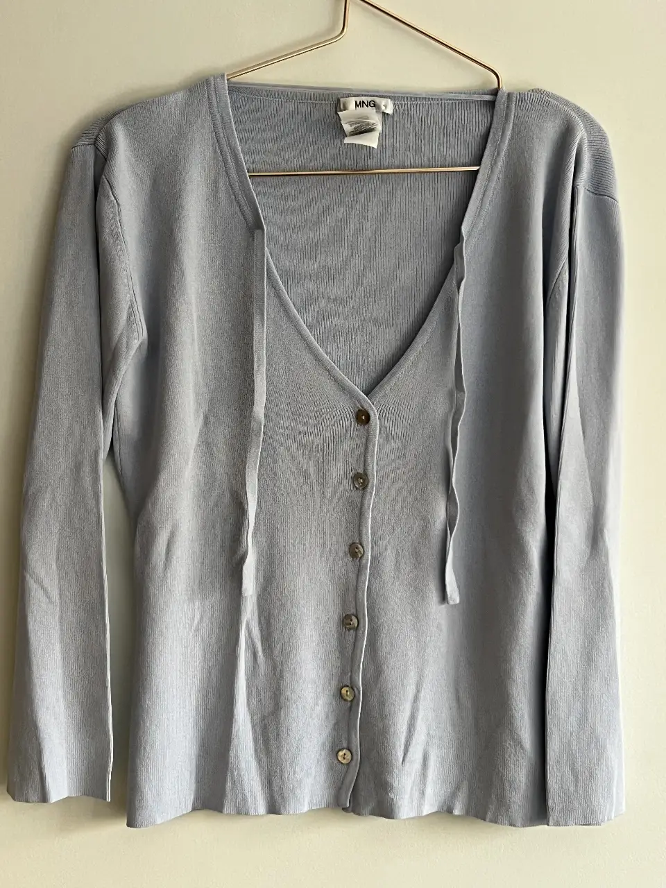 Cardigan celeste de manga larga con botones y lazo. Ideal para un look casual y cómodo.