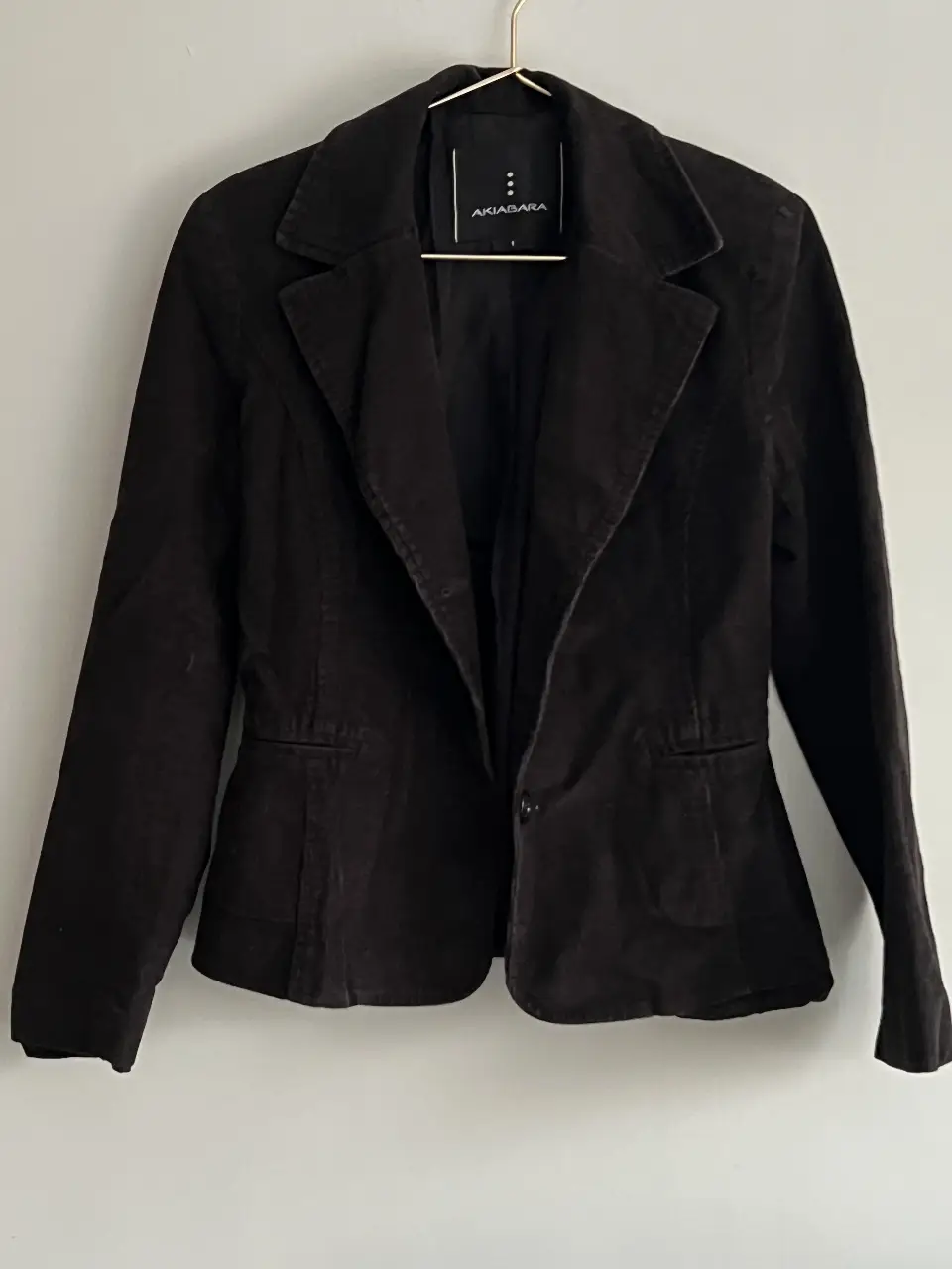Blazer negro de corderoy, con un solo botón y corte entallado. Ideal para un look elegante y sofisticado.