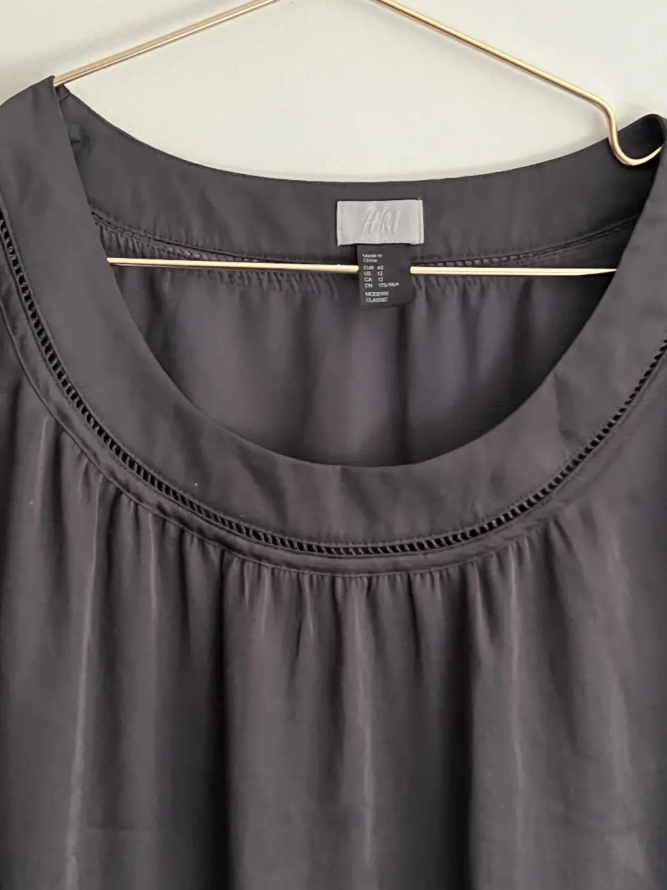 Vestido midi negro de H&M, con cuello redondo y detalle de costura en el escote y mangas cortas. Ideal para una salida elegante.