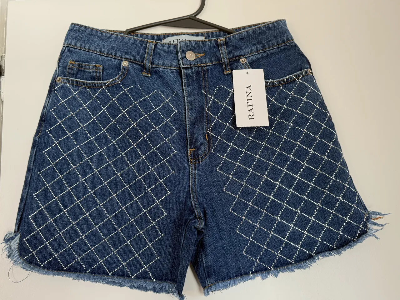 Shorts de jean tiro alto con tachitas plateadas en forma de rombos. Poseen rotura desflecada en el ruedo. Ideales para un look canchero y moderno.