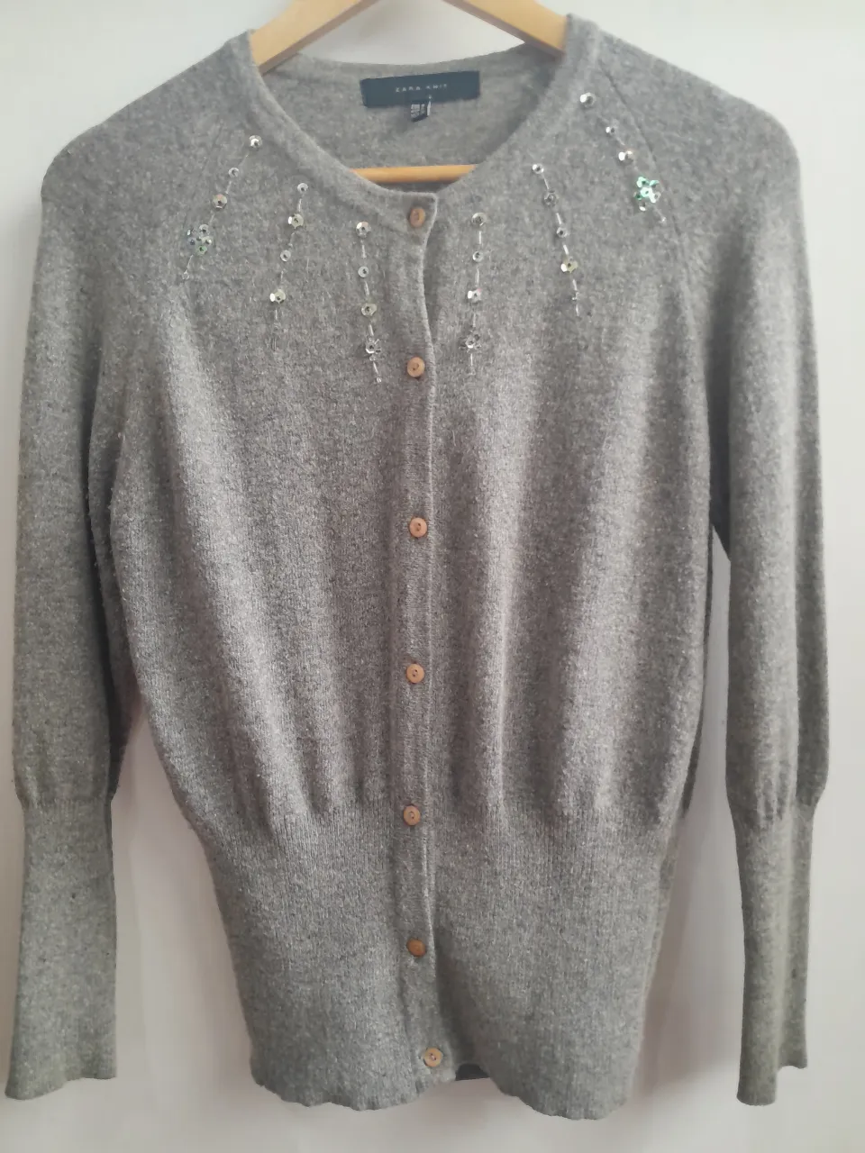 Cardigan gris de Zara Knit con lentejuelas en el frente. Medidas: 43 de sisa y 60 cm de largo. Ideal para un look elegante y sofisticado.