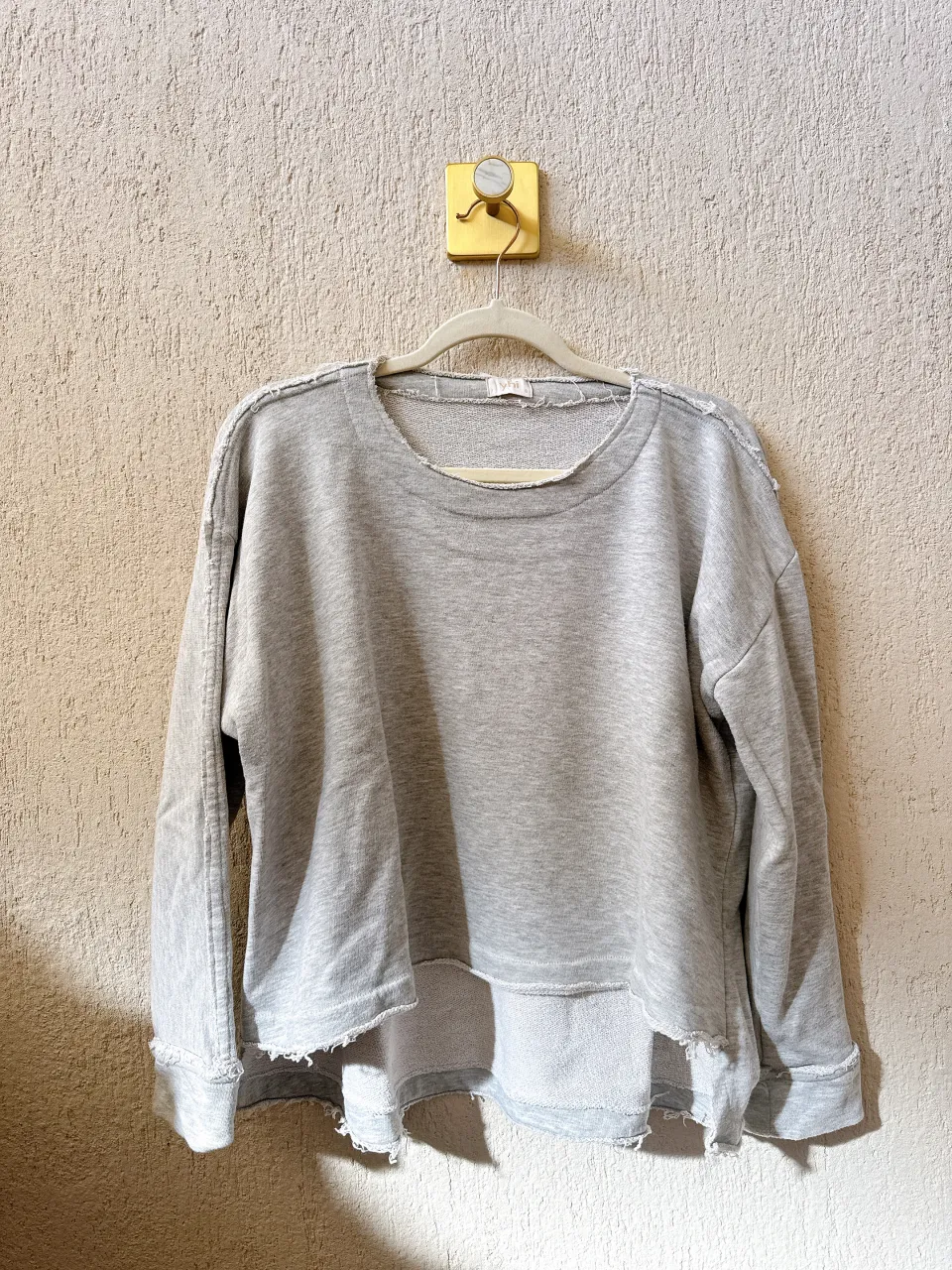 Remera gris de algodón con mangas largas y cuello redondo. Posee un diseño deshilachado en los bordes y un corte irregular en la parte inferior, dándole un toque moderno y casual. Ideal para el día a día. Medidas
Largo total 51cm adelante 66cm atrás 
Ancho de hombro 20cm
Largo de manga 48cm
Sisa a sisa 71cm