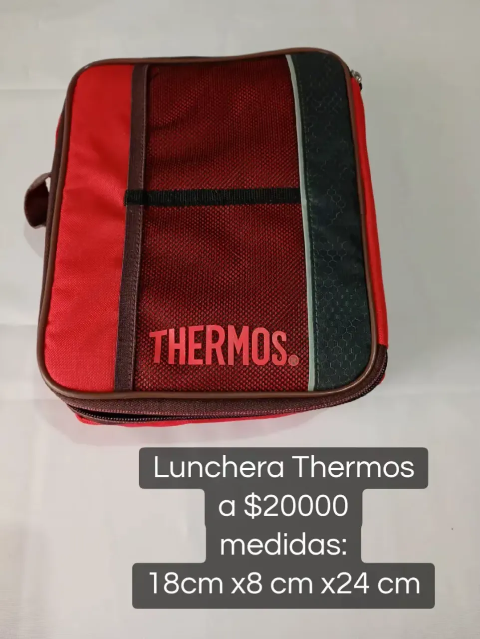 Lunchera Thermos de color rojo y detalles en negro y verde. Posee cierre y manija lateral. El interior es plateado y térmico.