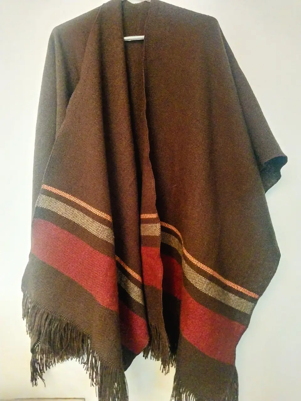 Poncho salteño original, marrón con detalles en rojo y crudo. Ideal para el invierno, con flecos en el borde.