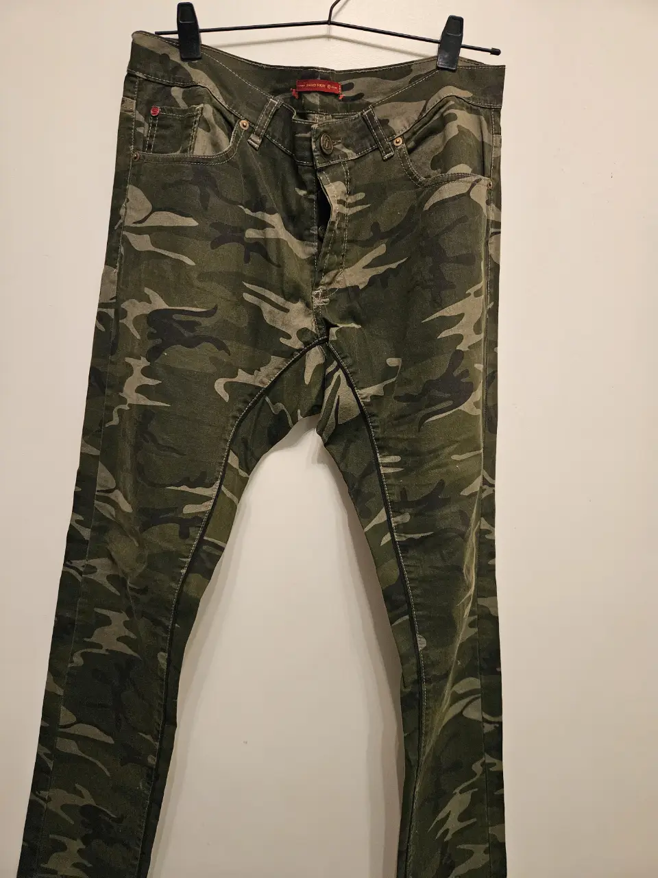 Pantalón de jean para hombre con estampado camuflado en tonos verdes y grises. Corte recto, ideal para un look casual y urbano. Perfecto para combinar con remeras y zapatillas.