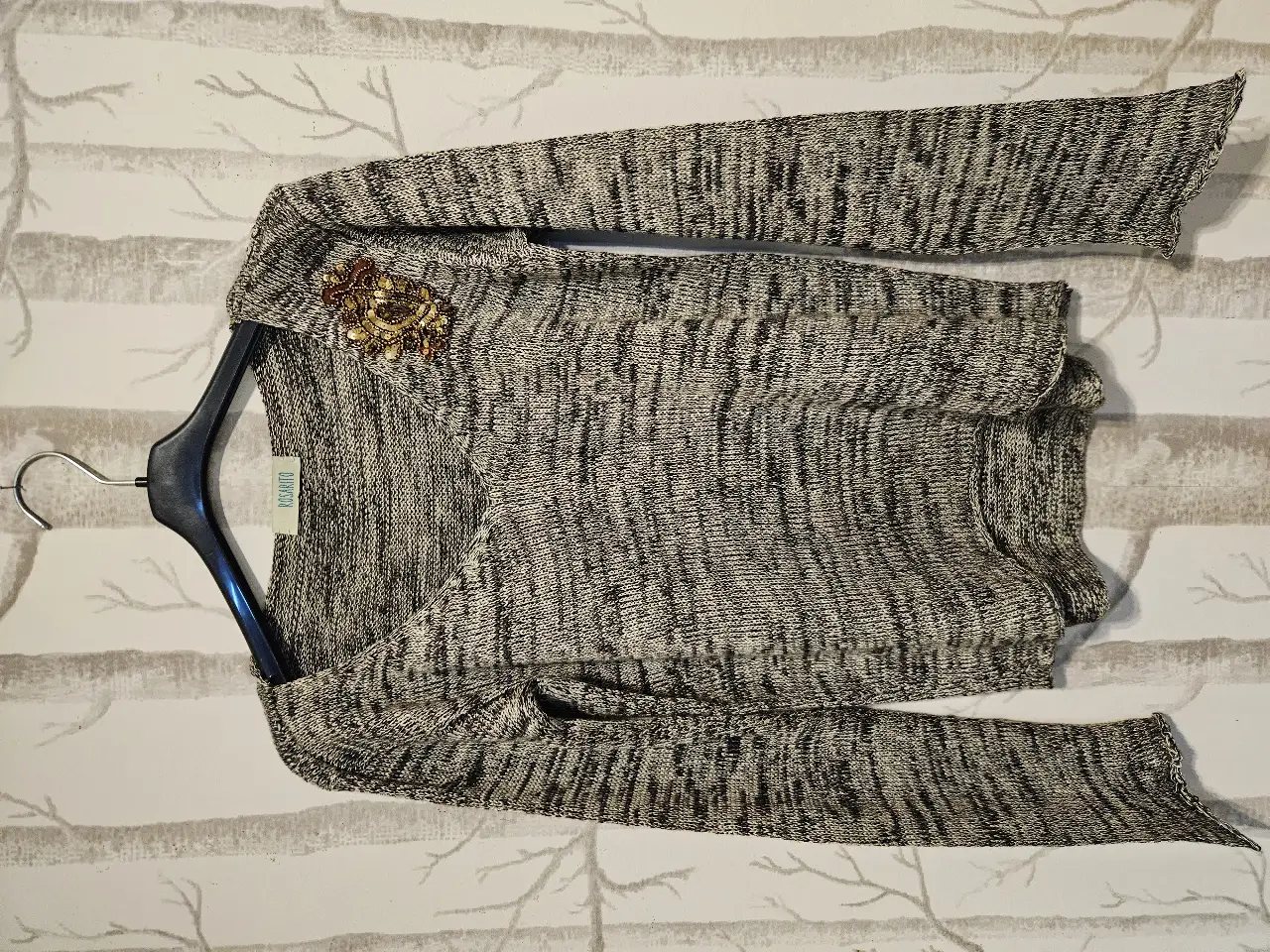 Sweater de punto con diseño jaspeado en tonos grises y negros. Detalle de bordado en lentejuelas y canutillos decorativo. Ideal para un look casual.