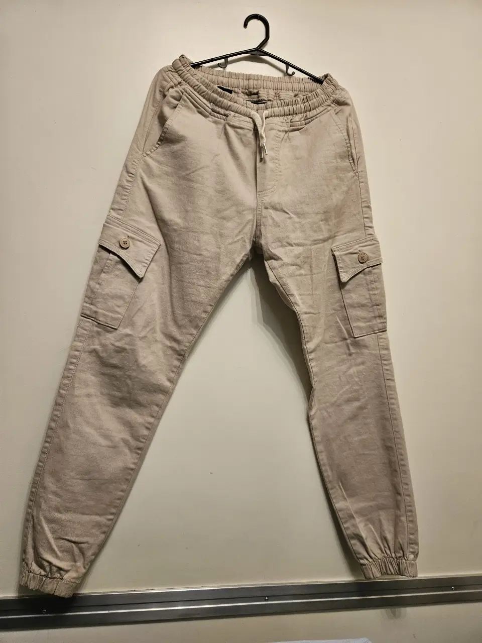 Pantalón cargo de hombre en color crudo, con bolsillos laterales y ajuste en los tobillos. Ideal para un look casual y cómodo.