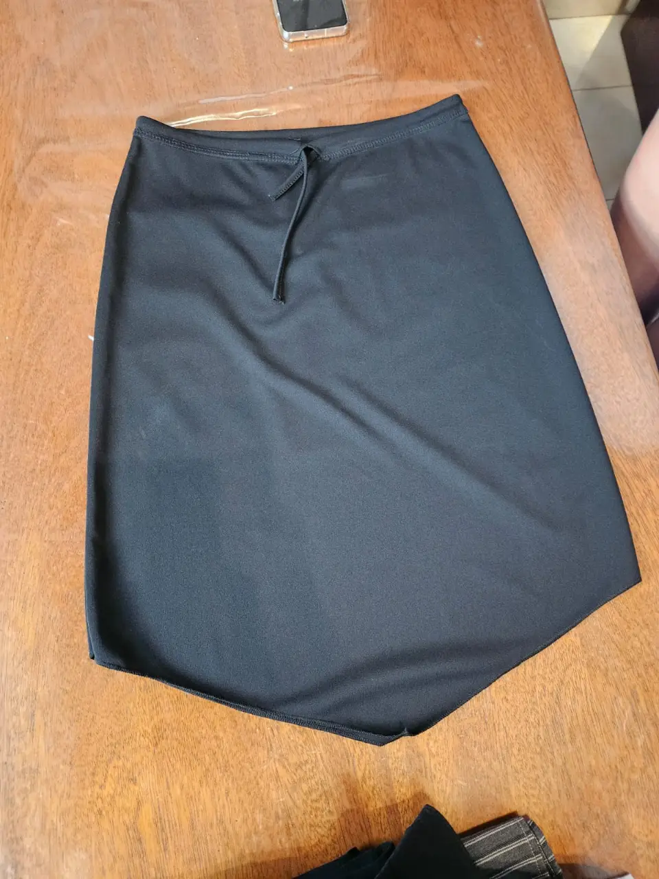Pollera negra elastizada, con un diseño asimétrico evase y un detalle de ajuste con cordón en la cintura. Ideal para un look casual y versátil. talle S
