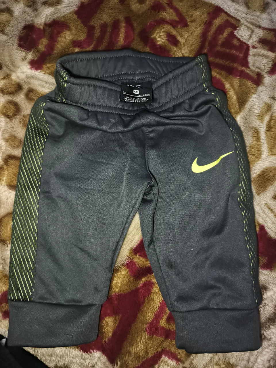 Conjunto de pantalón y body para bebé. El pantalón es gris con detalles en verde lima y el body es blanco con estampa de elefantes en celeste y gris.