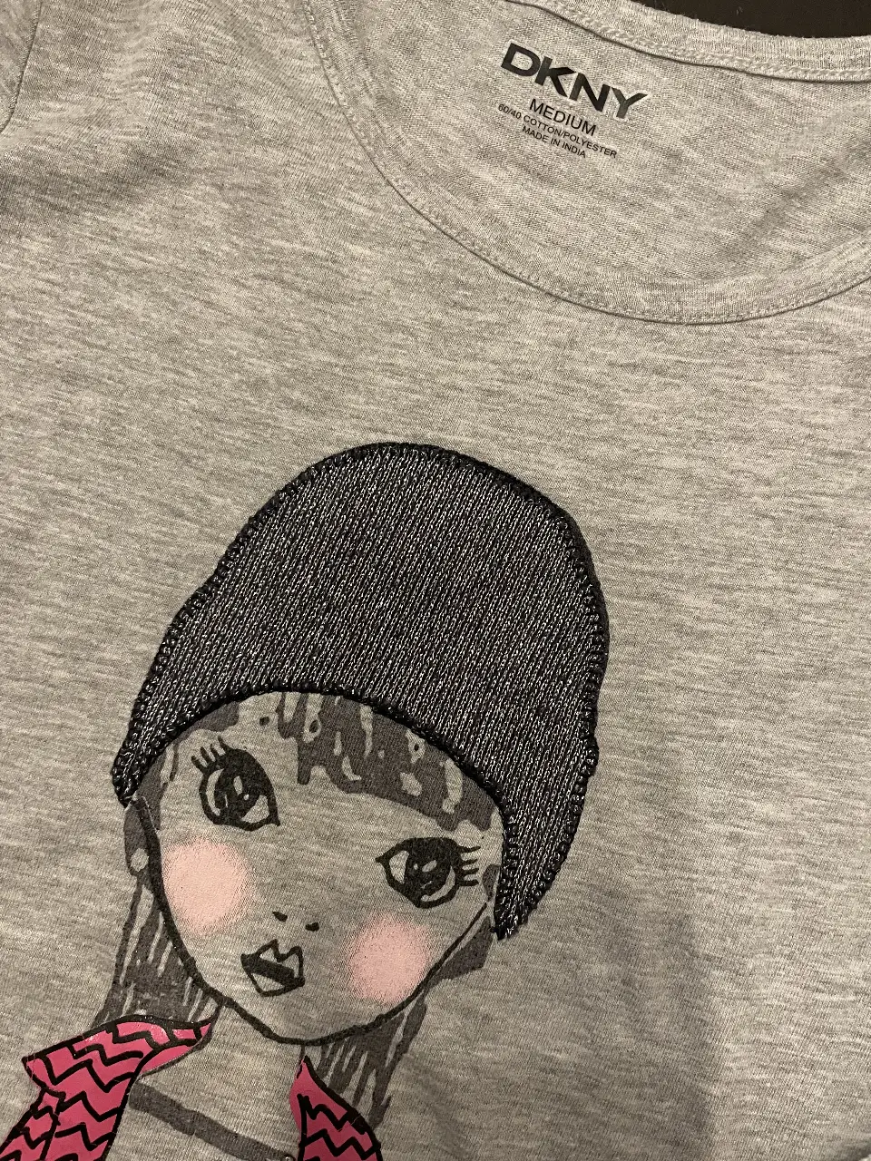 Remera manga larga gris para niña con estampado de una chica con gorro y bufanda rosa. Ideal para un look casual y moderno.