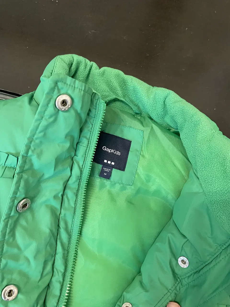 Chaleco verde GapKids para niña, acolchado con detalles de volantes y cierre. Ideal para el invierno.