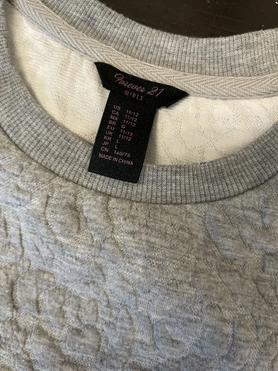 Buzo de cuello redondo gris con textura en relieve, ideal para un look casual y cómodo. Perfecto para el día a día.