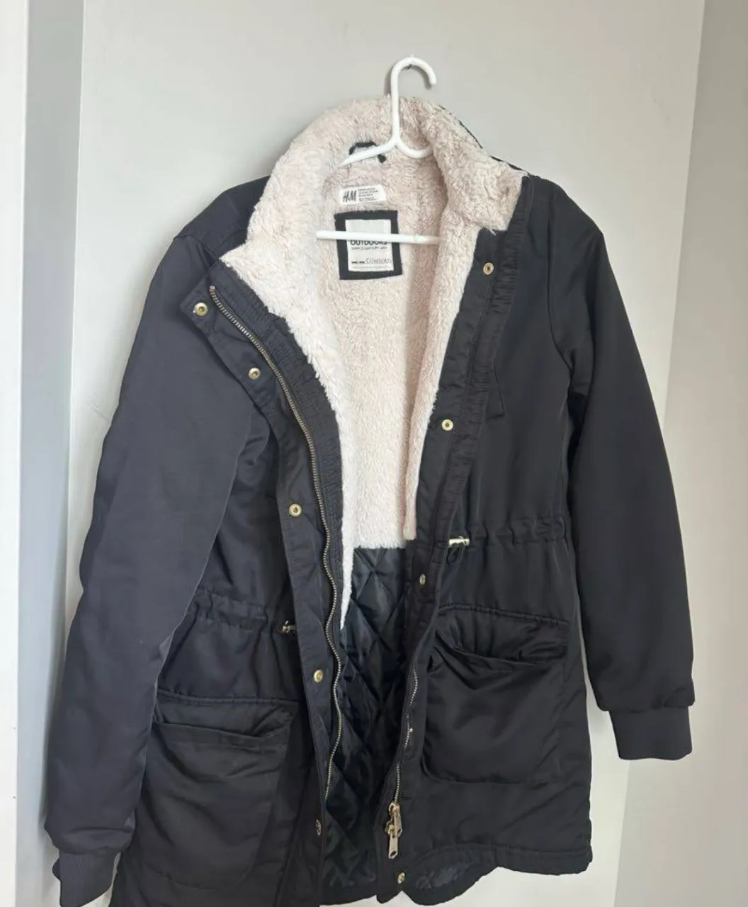 Campera negra de H&M, forrada con corderito súper suave y abrigada. Ideal para días fríos y lluviosos, con bolsillos amplios y ajuste en la cintura para un calce perfecto. Un básico indispensable para el invierno.