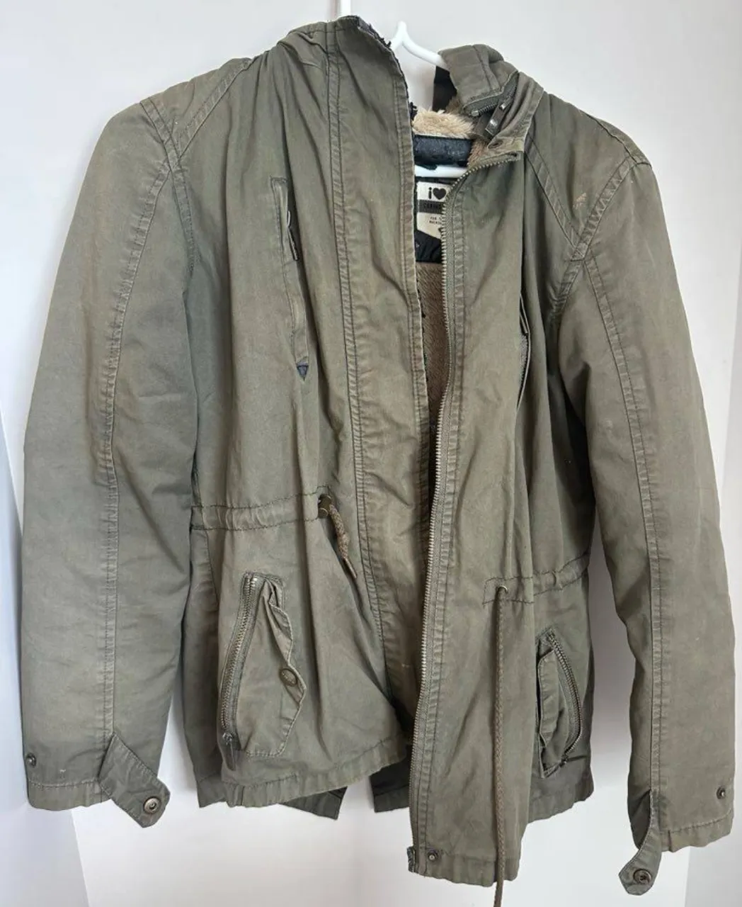 Campera de abrigo forrada en peluche, ideal para el frío. Posee capucha, múltiples bolsillos con cierre y cordón ajustable en la cintura para un mejor calce. Perfecta para un look casual y abrigado. Cuero gastado en la parte del cierre