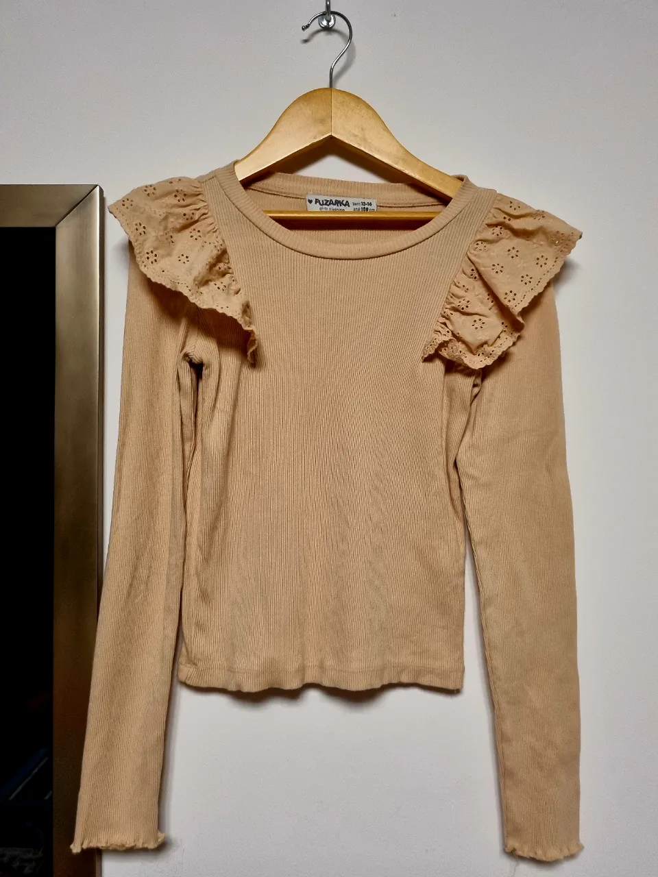 Remera manga larga de algodón acanalado en color tiza, con detalles de volados y puntilla en cuello y puños. Perfecta para un look canchero y delicado.