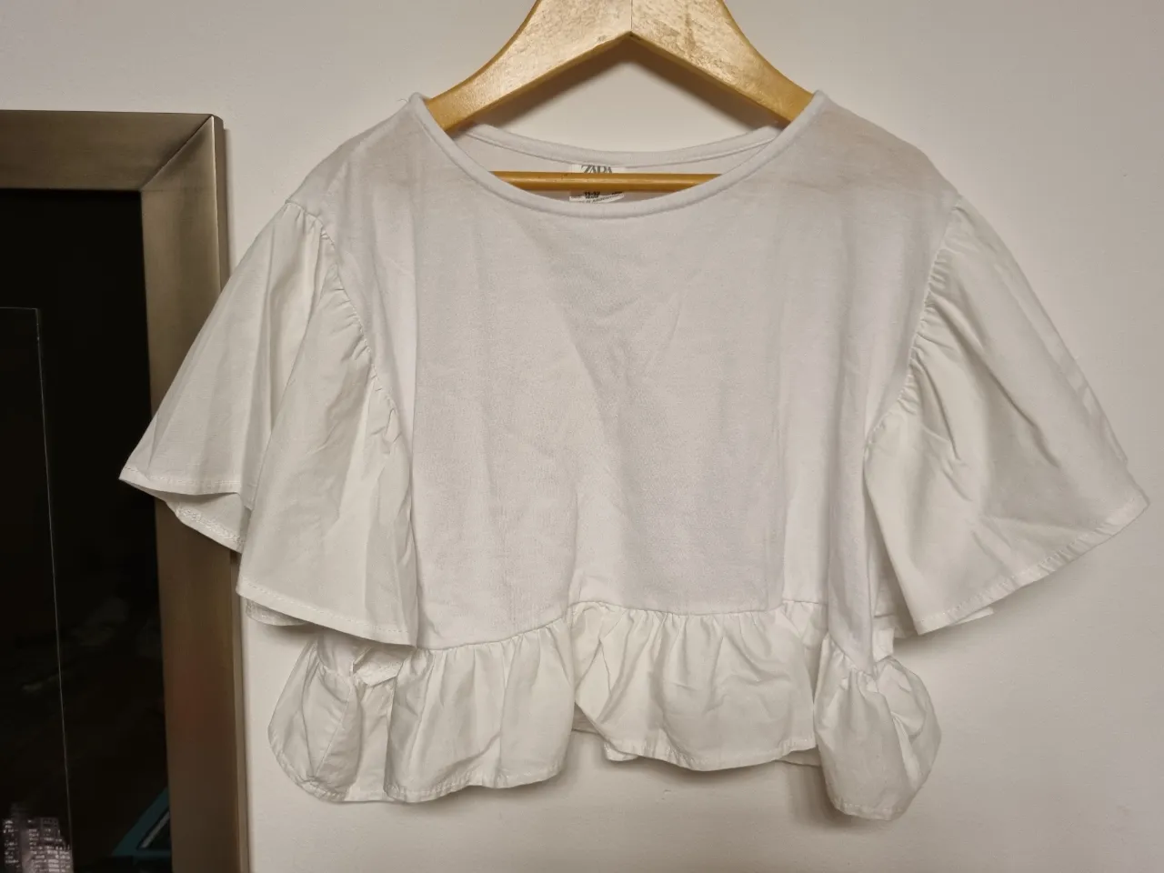 Remera blanca de algodón con mangas cortas y volados. Diseño moderno y fresco, ideal para el día a día.