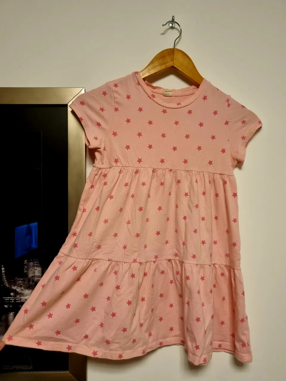 Vestido rosa con estampa de estrellas, ideal para niñas. Tiene un corte con dos volados, mangas cortas y cuello redondo. Perfecto para el día a día o para una salida informal.