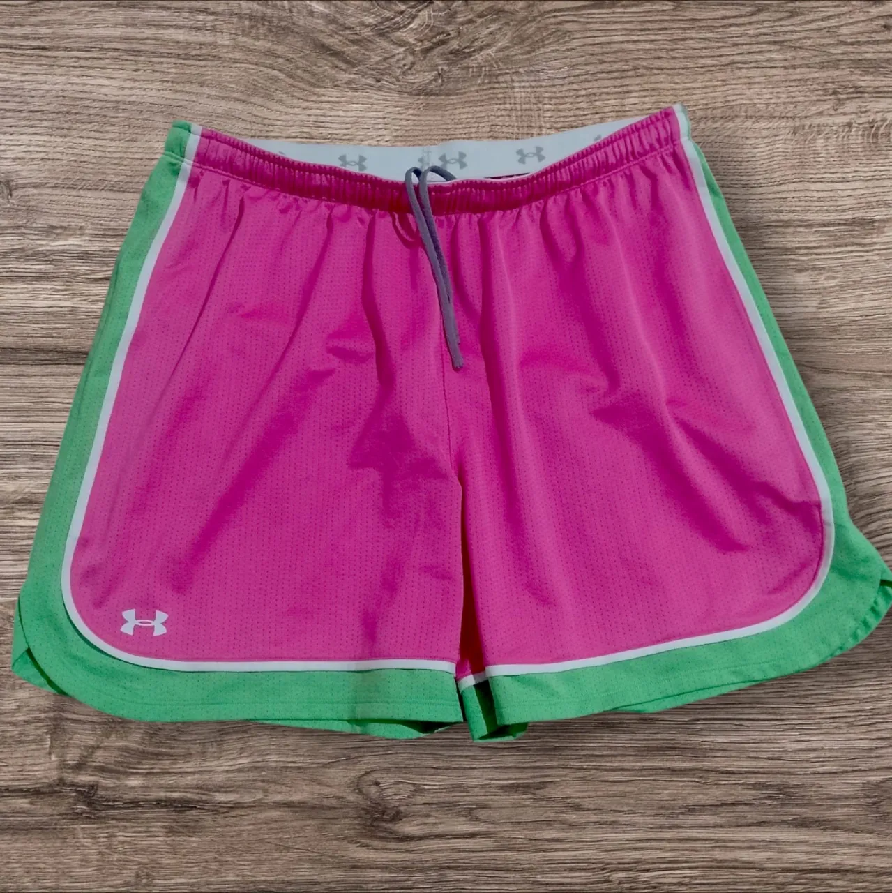 Shorts deportivos de mujer, color rosa vibrante con detalles en verde y blanco. Ideales para entrenar o para un look casual y cómodo.