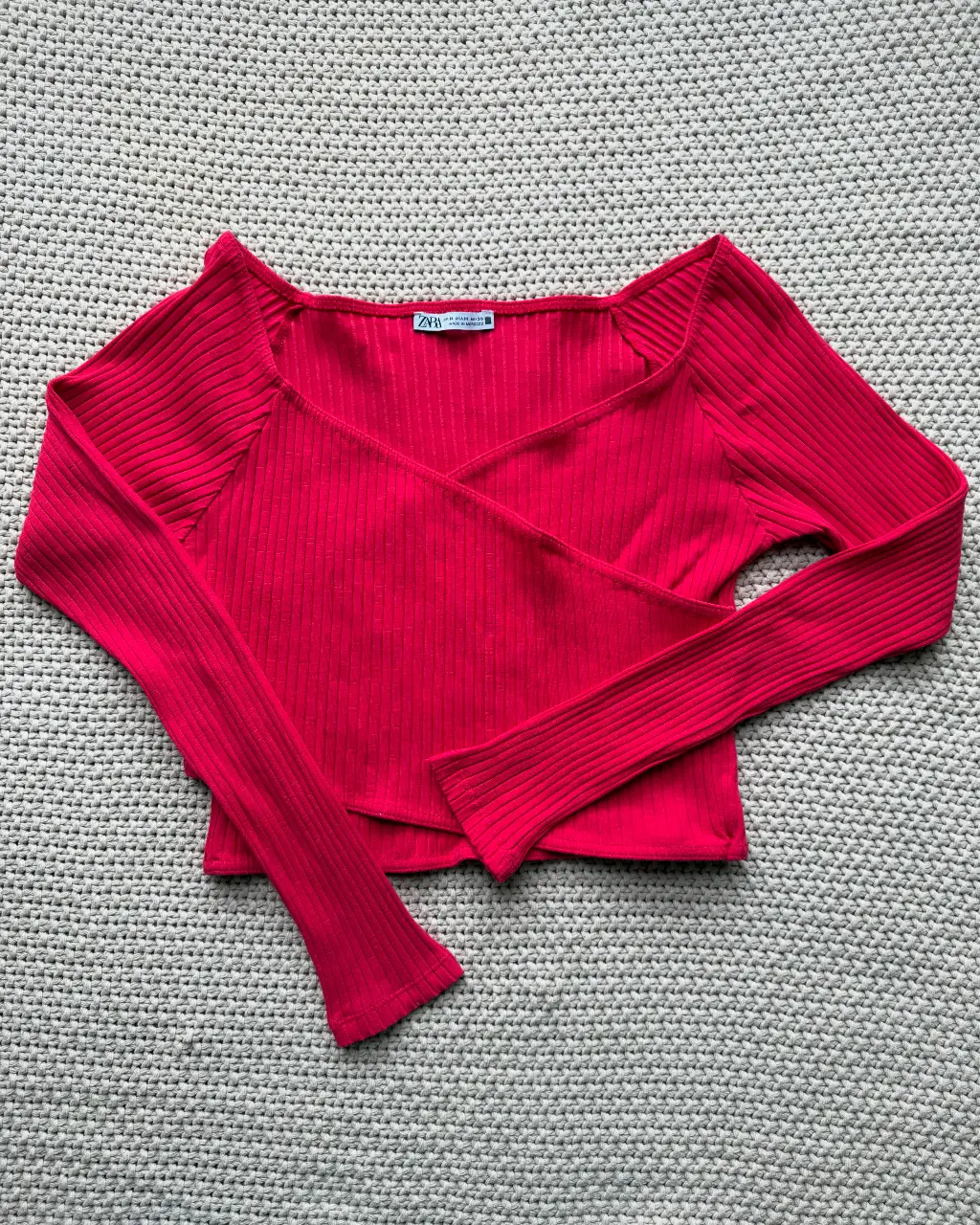 Top manga larga fucsia con diseño cruzado y corte ajustado. Ideal para un look moderno y audaz.