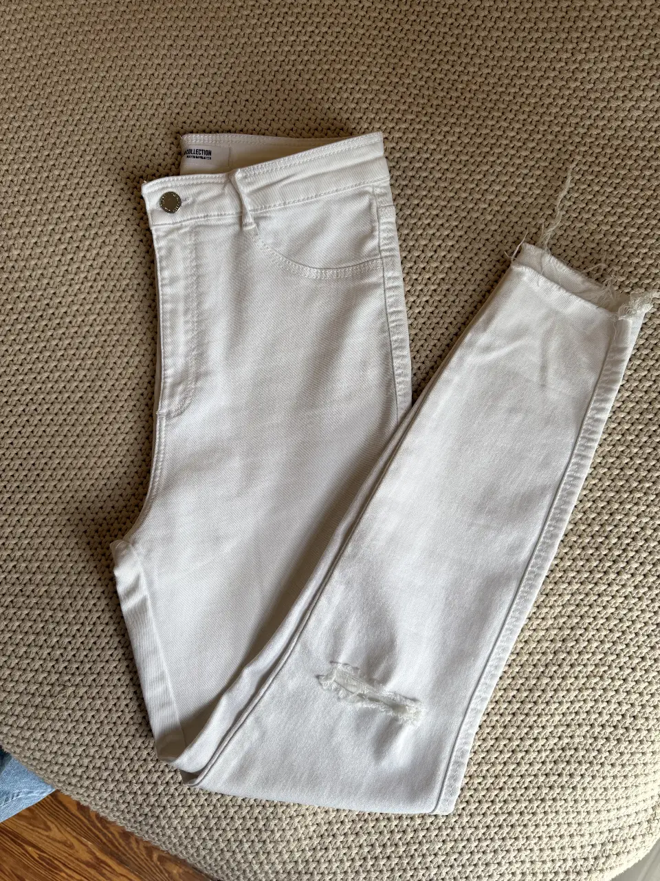 Jeans blancos con roturas en la rodilla, tiro alto y corte recto. Ideal para un look casual y moderno.