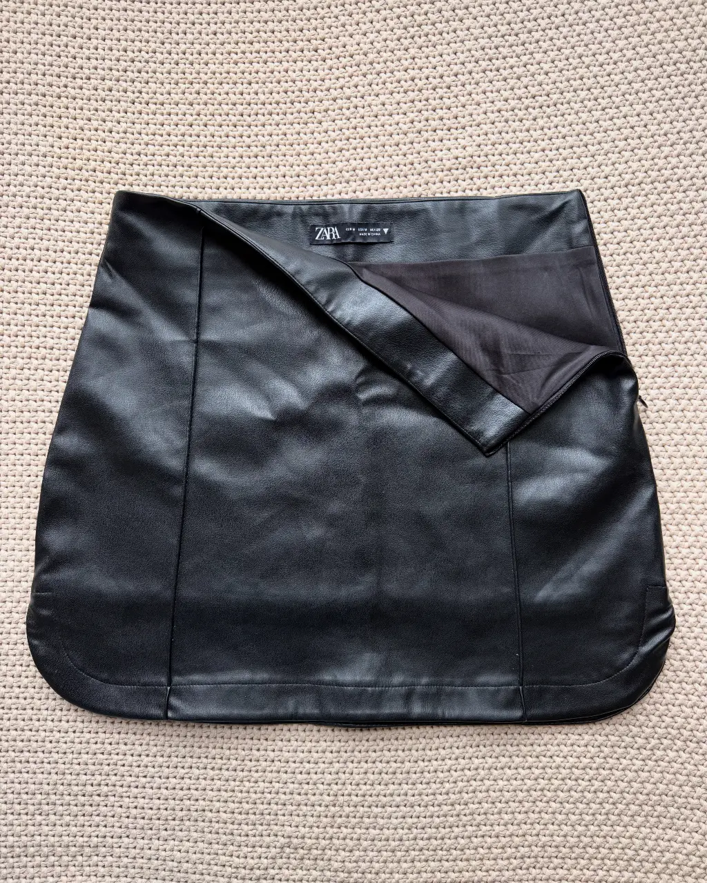 Pollera negra de cuero sintético de la marca Zara. Diseño con solapa y detalle de costura. Ideal para un look elegante y moderno. Talle M
