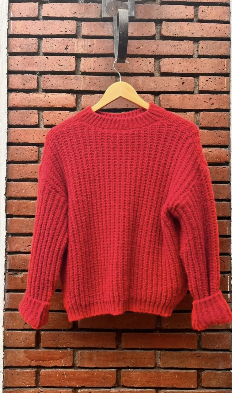 Sweater rojo de punto grueso, ideal para el invierno. Cuello redondo y mangas largas con puños.