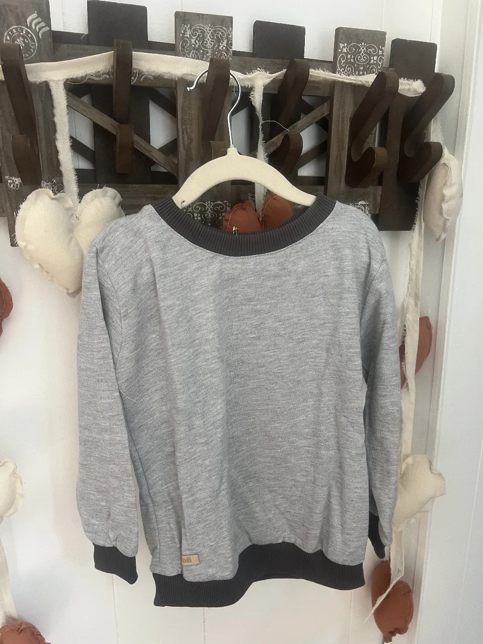 Buzo de cuello redondo gris con detalles en negro en puños y cuello. Ideal para un look casual y cómodo.