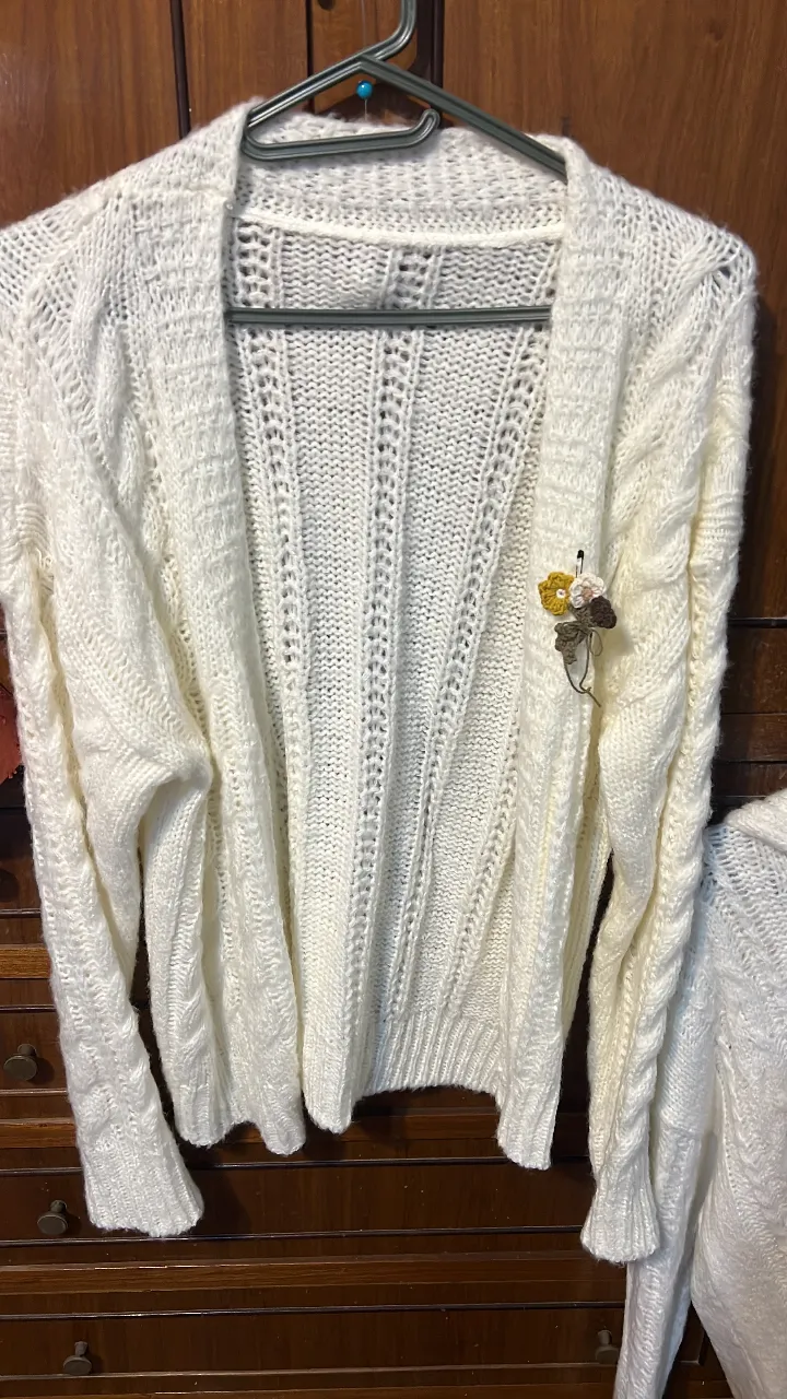 Cardigan tejido de color blanco con detalle de broche floral. Ideal para un look casual y abrigado.