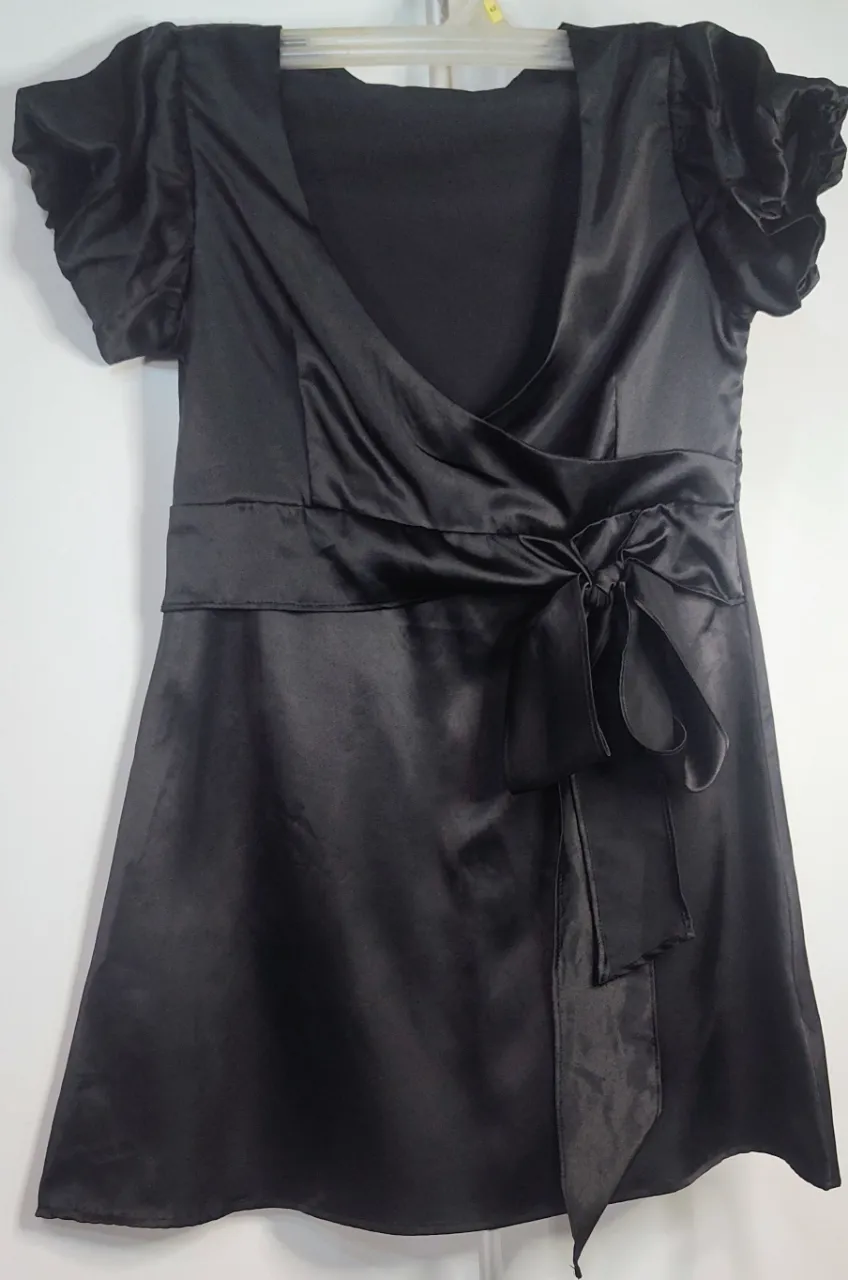 ¡Qué buena elección! Ese vestido de satén negro es una prenda súper versátil para cualquier evento especial. 👗 se trata de un vestido corto cruzado (wrap dress) con mangas cortas abullonadas y un lazo ajustable en la cintura. 38 cm de sisa a sisa.
