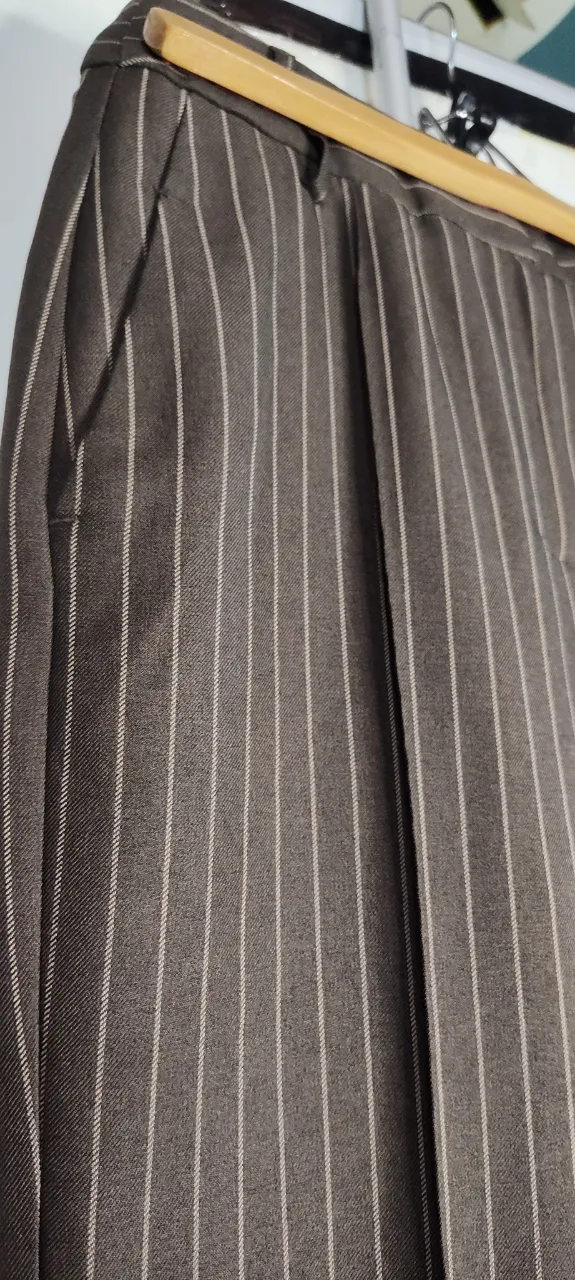 Pantalón de vestir de corte recto, con rayas verticales finas en color blanco sobre fondo marrón. Posee bolsillos laterales y un diseño clásico, ideal para un look formal o de oficina. se cintura 35cm.