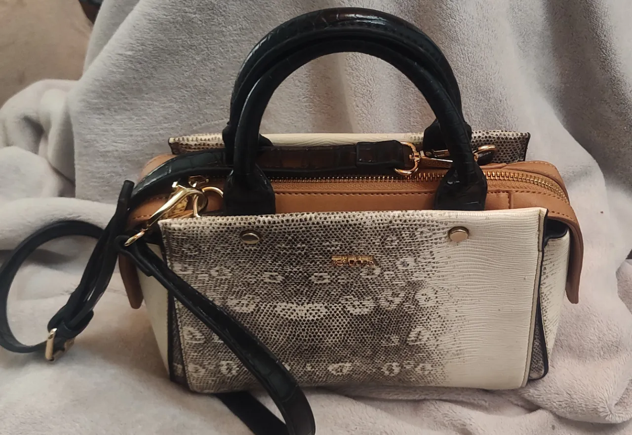 Realza tu aufiis ISIDORA💥💥 Cartera de mano con correa desmontable. Diseño texturizado con efecto piel de reptil y detalles en color blanco y marrón.  City textura reptil bicolor. Doble asa corta textura crocco. Asa larga regulable. Cierre de cremalle de alto 24 cm y 20 de ancho. 