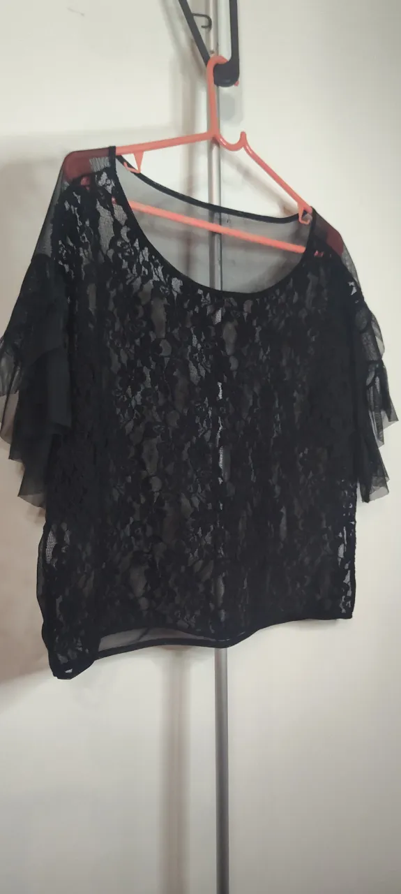  Remera de encaje negro de corte amplio y estilo romántico, caracterizada por su diseño transparente y mangas cortas tipo "capita" con volados. Es una pieza versátil, ideal para eventos de noche o fiestas, generalmente utilizada sobre una musculosa o prenda base.  negra de encaje con mangas cortas con volados de tul. Talle 44 de sisa a sisa 50 cm.