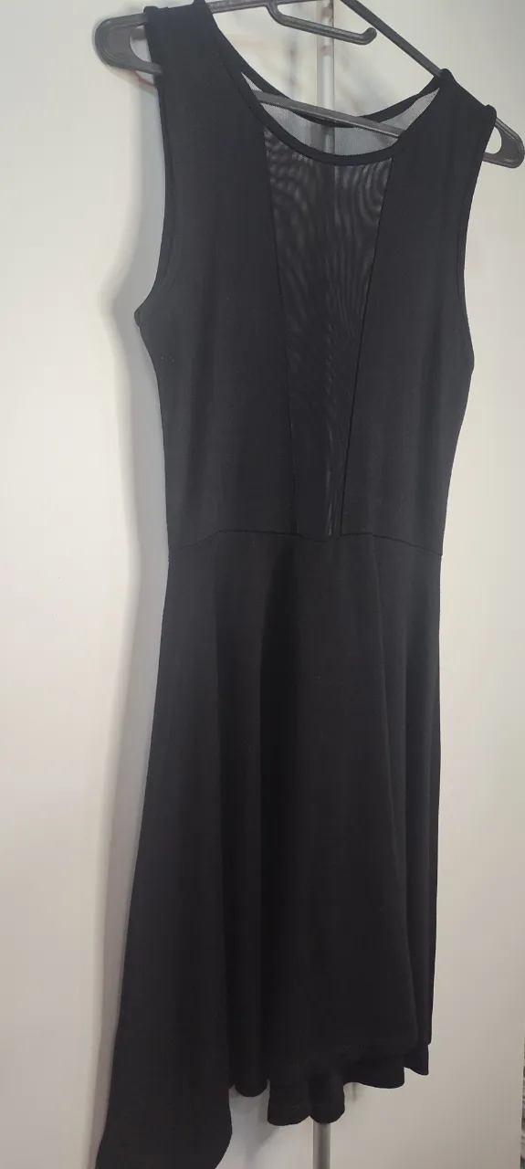 Divino!!Este vestido es un modelo de corte acampanado (skater) en color negro, caracterizado por un panel frontal de malla de tul transparente en forma de V que se extiende desde el cuello hasta la cintura, negro sin mangas con escote en V de tul. de sisa a sisa 38.