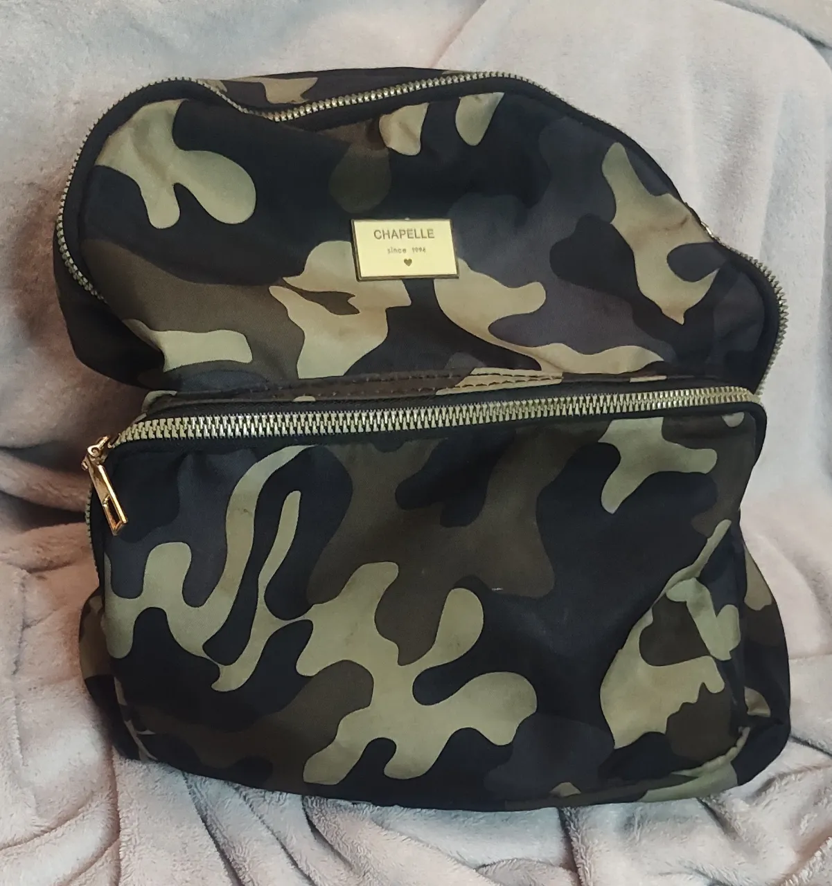 Mochila con estampado de camuflaje. Tiene un bolsillo principal con cierre y un bolsillo frontal también con cierre. Las correas son ajustables. medidas de alto 37 cm y de ancho 30.cm