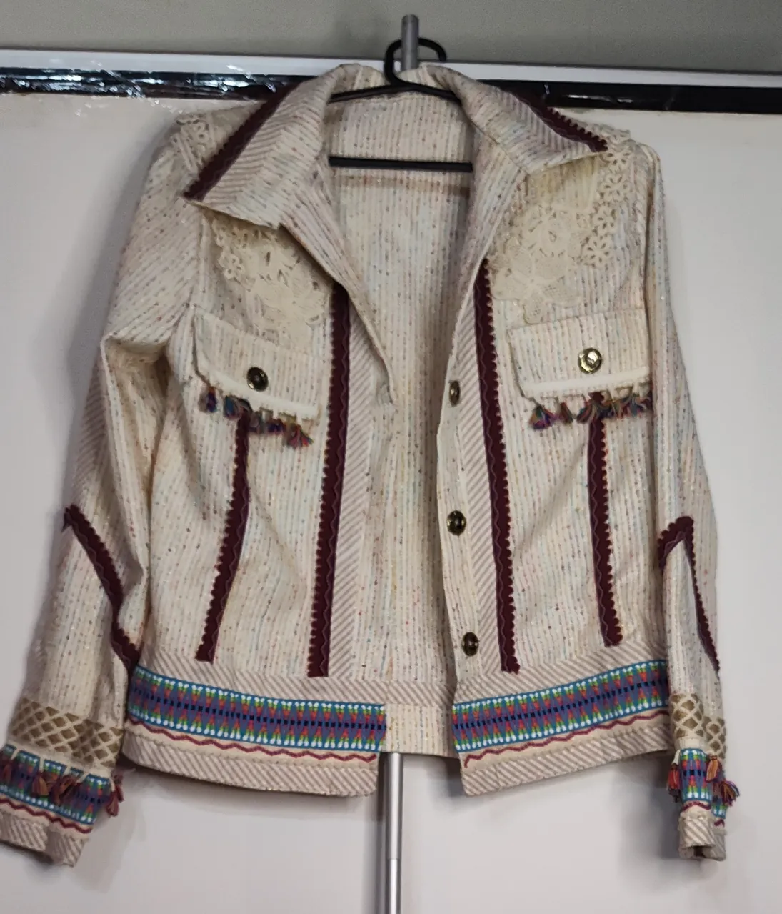 Chaqueta de diseño único, con detalles de flecos y bordados coloridos. Ideal para darle un toque bohemio, Incluye aplicaciones de encaje guipur en la parte superior, cintas bordadas con motivos geométricos y terminaciones con flecos multicolores y pompones hermosa y única.