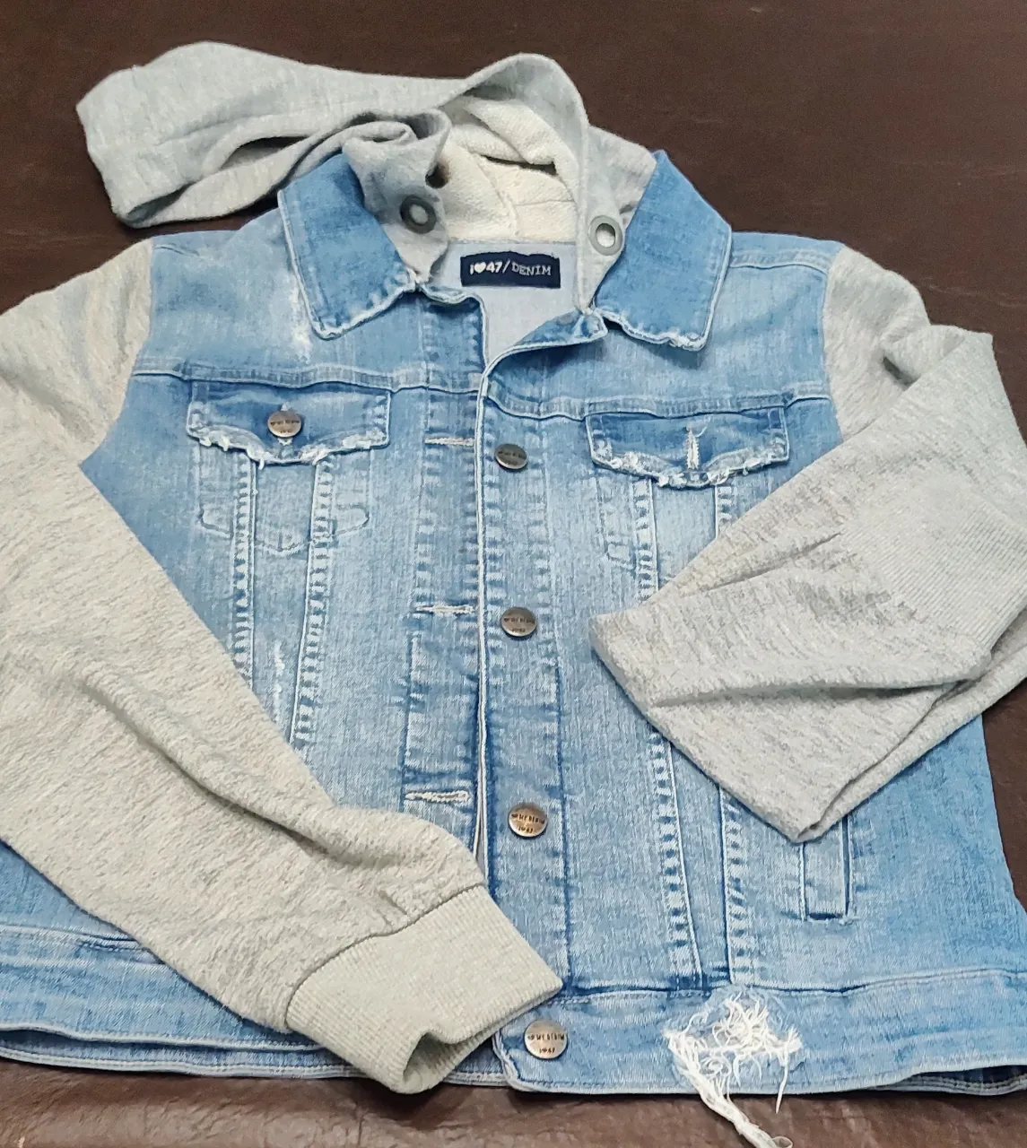 47❤️Campera de jean con mangas y capucha de algodón gris. Tiene detalles de roturas y botones metálicos.