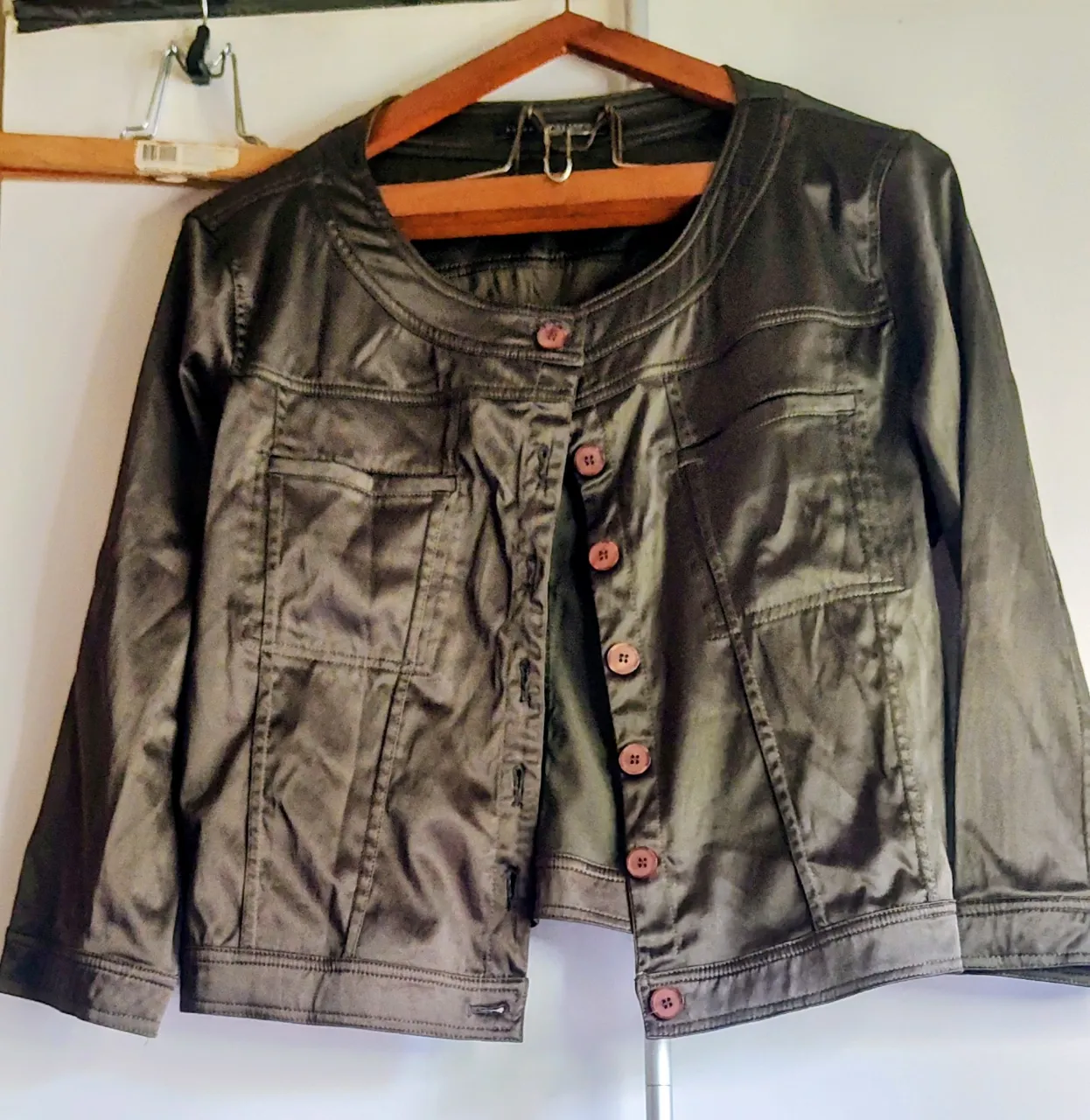 súper REBAJA 💥 💥 💥 chaqueta fina tipo cazadora con un acabado satinado o encerado en un tono verde oliva oscuro  corta de moldería moderna, con botones al frente y bolsillos. Ideal para un look canchero y versátil.