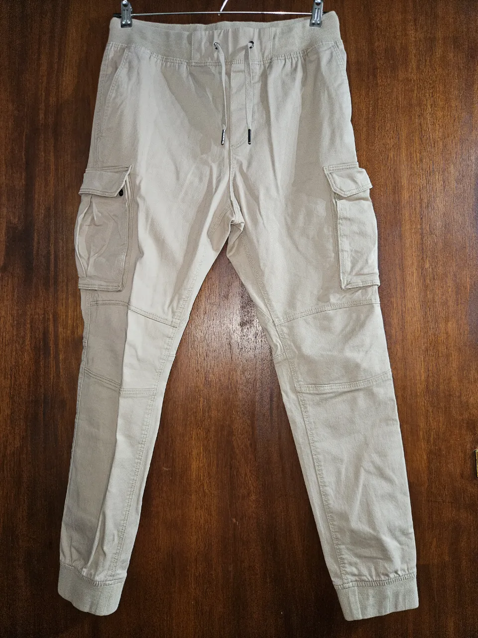 Pantalón cargo de algodón color beige H&M, con bolsillos laterales y cintura elastizada con cordón. Estilo jogger, ideal para un look casual y cómodo.