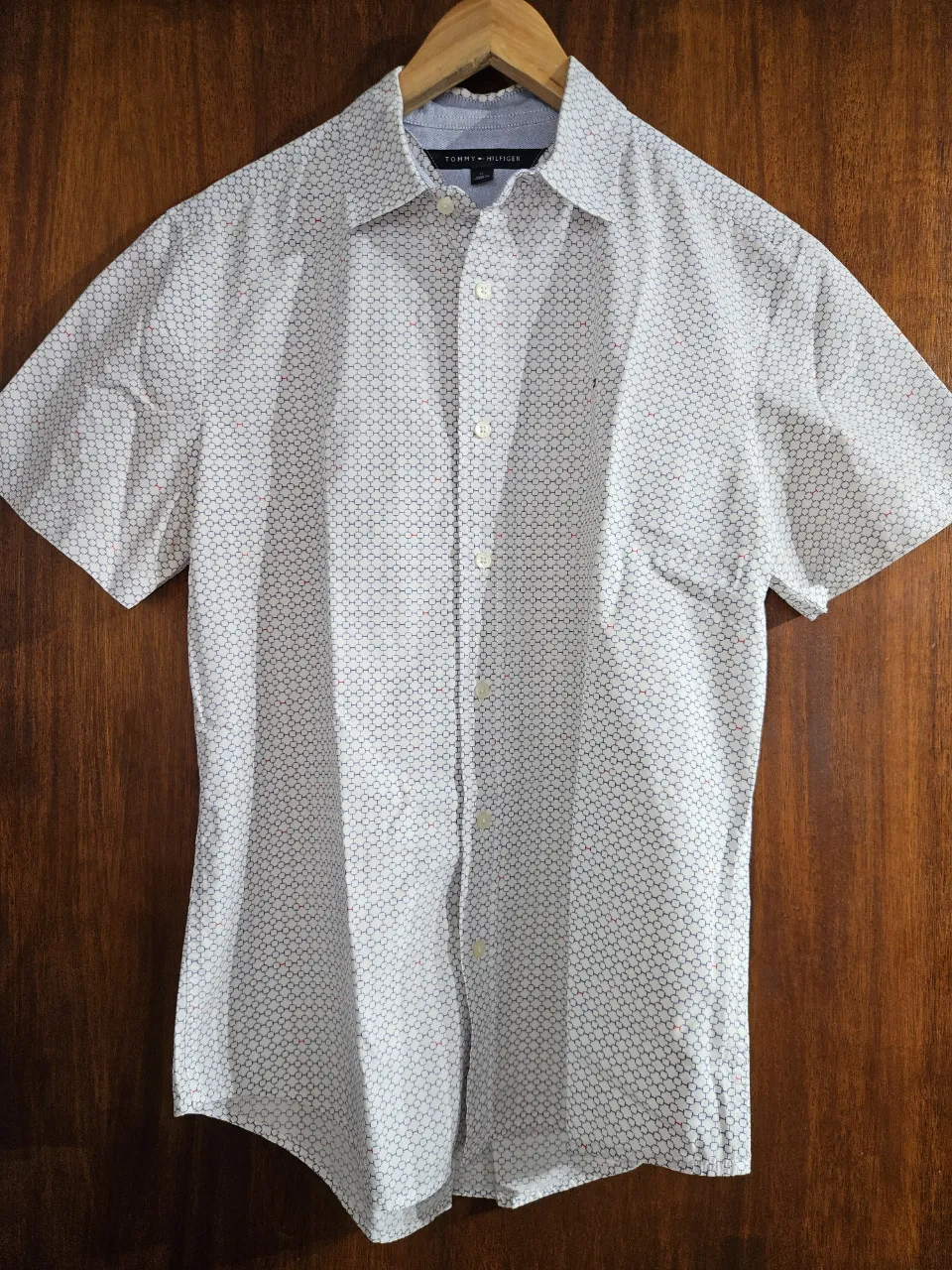 Camisa de hombre Tommy Hilfiger, manga corta, con un estampado geométrico discreto en blanco y azul con pequeños detalles en rojo. Ideal para un look casual y moderno.