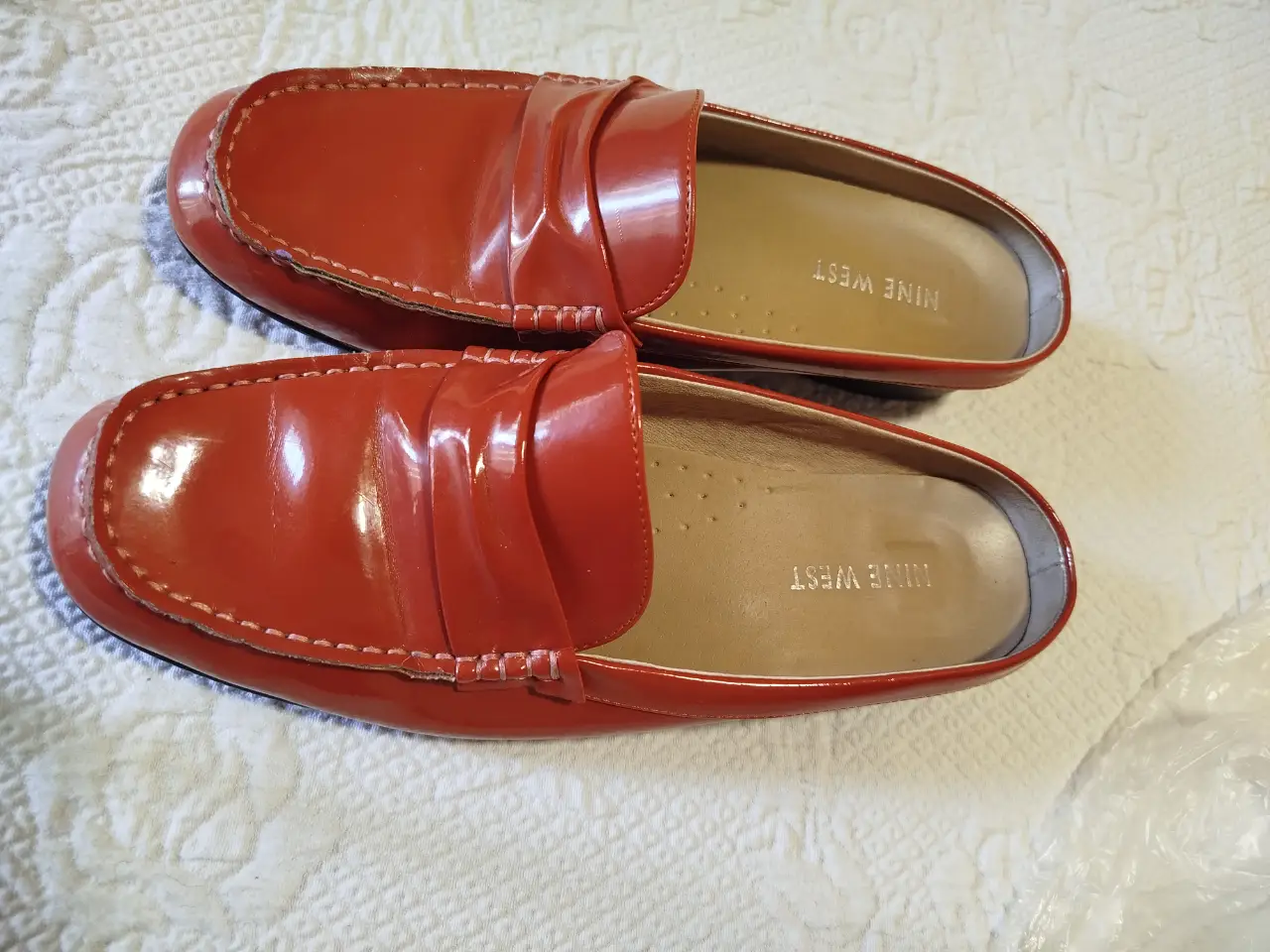 Mocasines de mujer color anaranjado, de charol, con detalle de costuras y la marca Nine West en la plantilla. Ideales para un look elegante y cómodo.