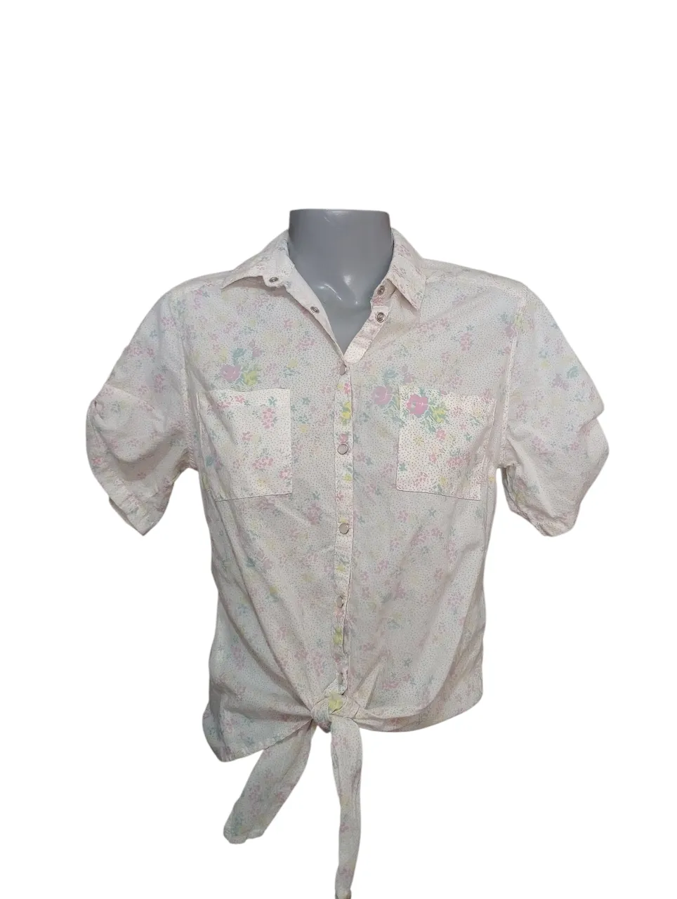 Camisa de mangas cortas con estampado floral y lunares. Posee dos bolsillos en el frente y se anuda en la parte inferior.