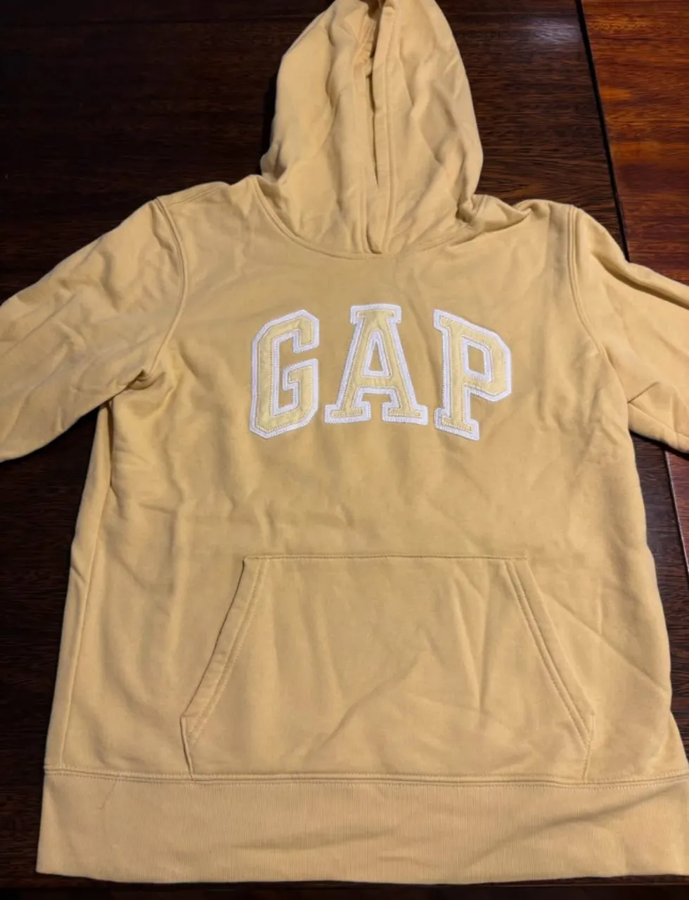 Buzo canguro GAP amarillo con logo blanco en el frente. Ideal para un look casual y cómodo.