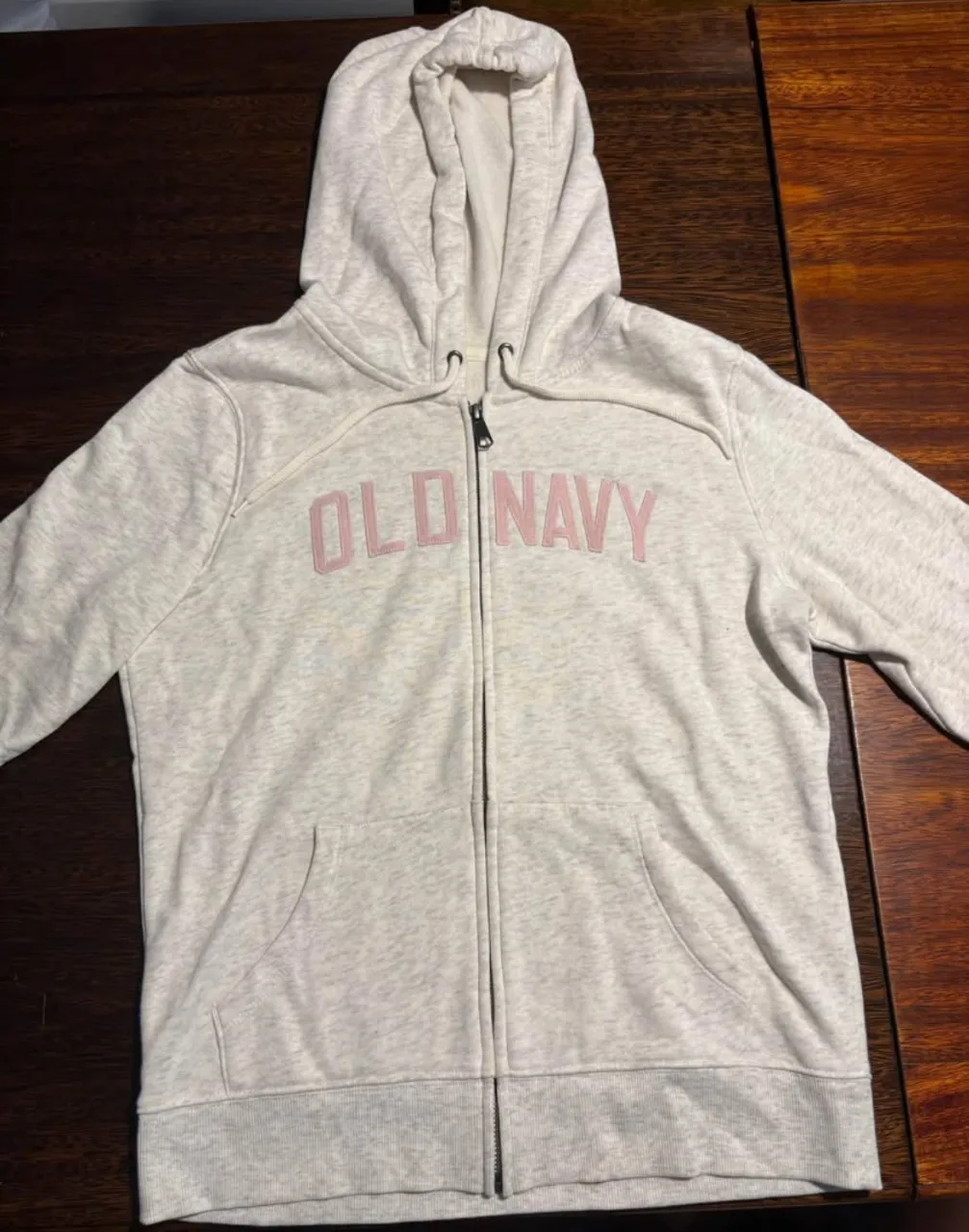 Buzo con cierre y capucha de la marca Old Navy, color gris con letras rosas. Ideal para un look casual y cómodo.