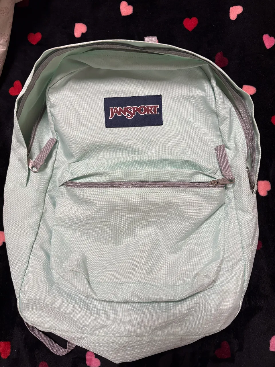 Mochila Jansport verde agua, ideal para llevar tus cosas con estilo y comodidad. Perfecta para el día a día.
