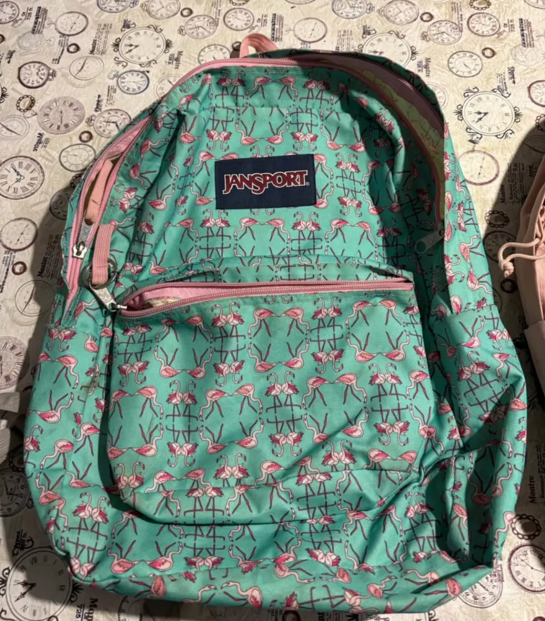 Mochila Jansport con estampado de flamencos en tonos turquesa y rosa. Ideal para llevar tus cosas con estilo y comodidad.