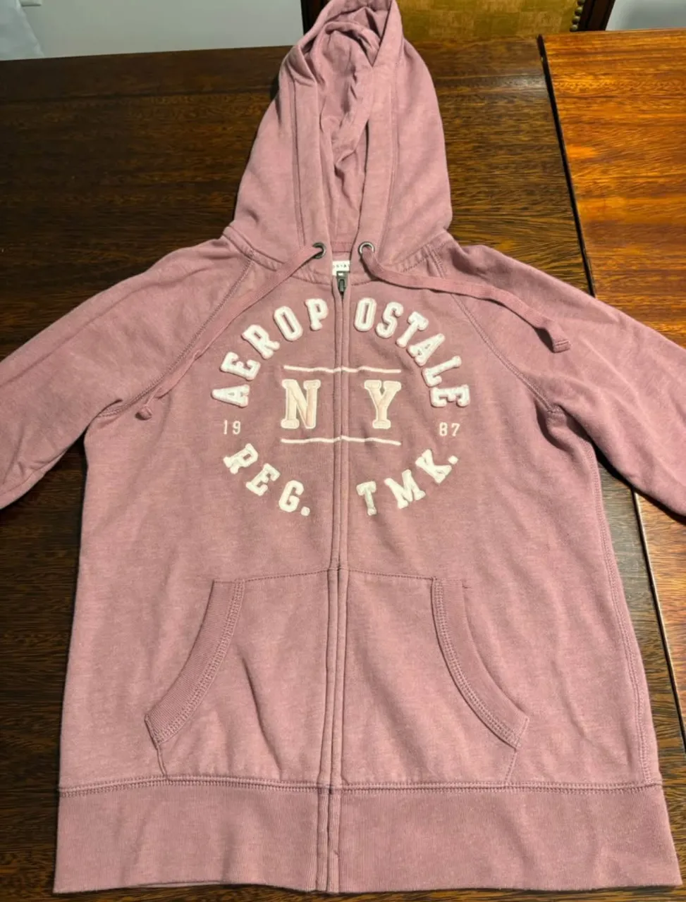 Buzo con cierre y capucha para mujer, de color rosa. Marca AEROPOSTALE. Ideal para un look casual y cómodo. 
