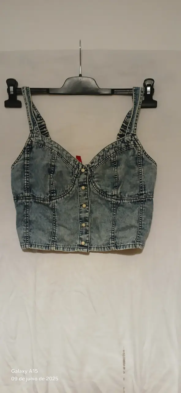 Top de jean azul con broches delanteros y tirantes. Ideal para un look casual y moderno.
