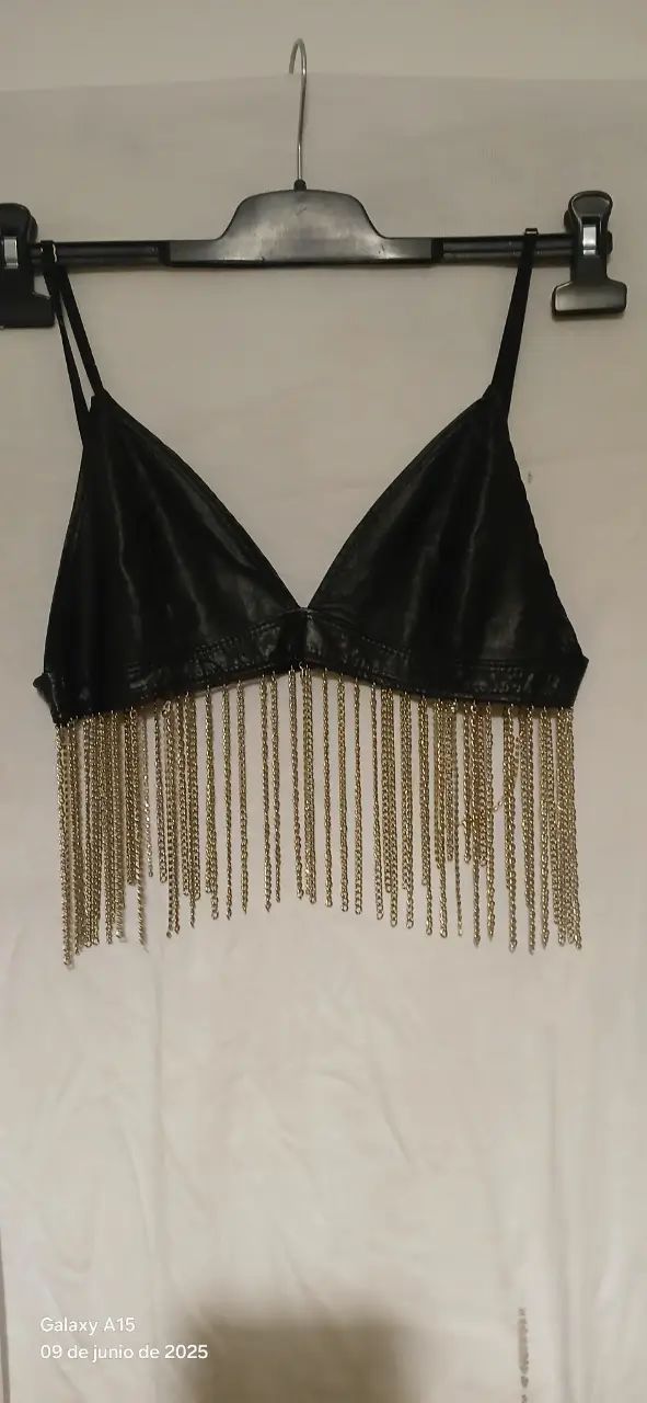 Top negro con flecos dorados, ideal para fiesta. Confeccionado en material similar al cuero, con detalles de cadenas doradas.