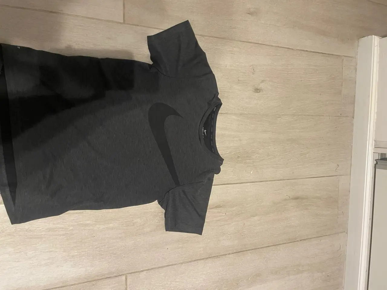 Remera deportiva Nike de hombre, color gris oscuro, con el logo de la marca en negro. Ideal para entrenamientos.
